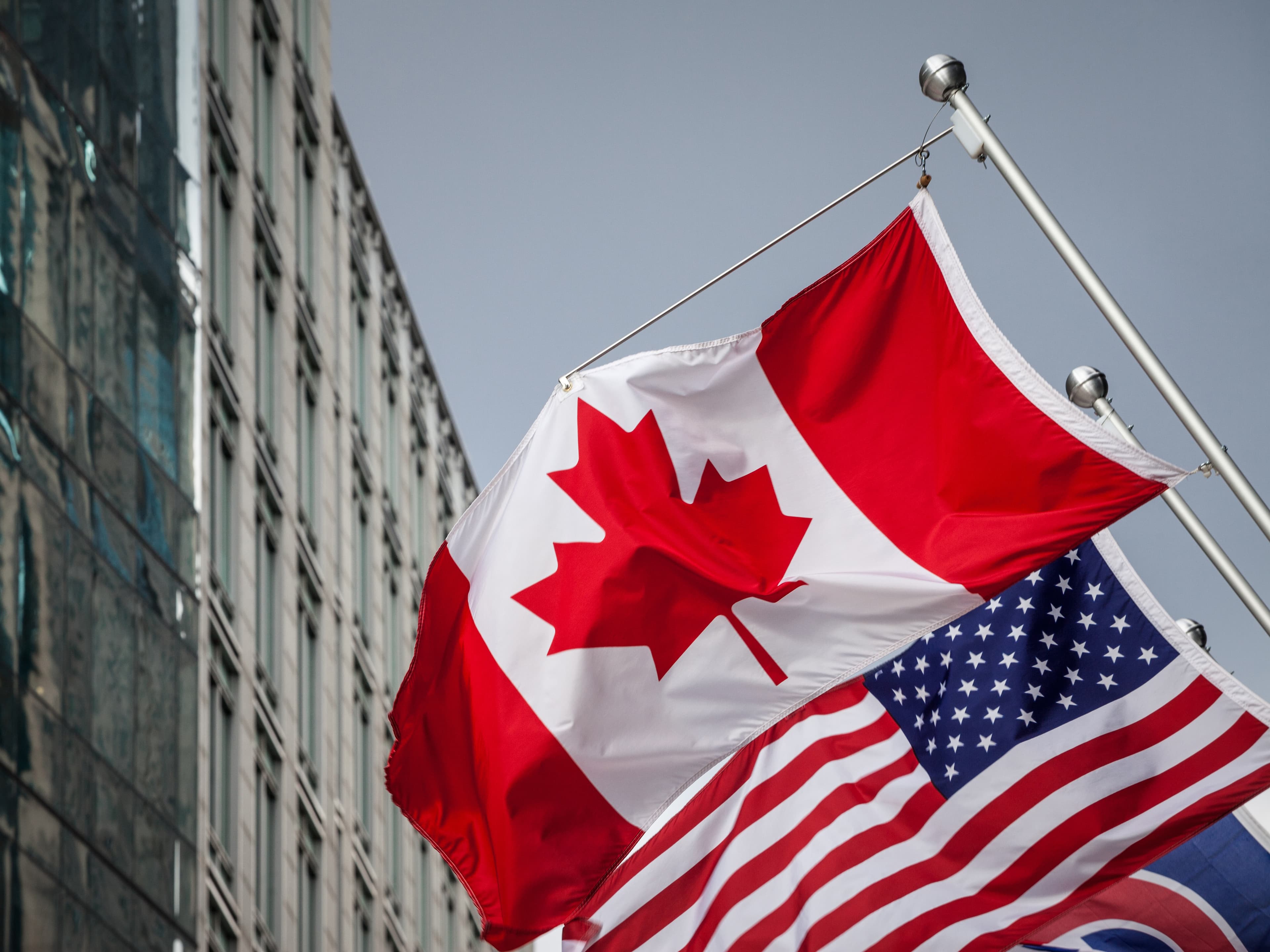 Drapeau canadien et americain flottant devant le batiment du centre-ville